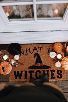 a person standing in front of a witches door mat with candles and pumpkins around it