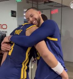 two men in blue and yellow uniforms hugging each other