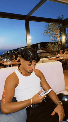 a man sitting in a restaurant looking at his cell phone and writing on the paper