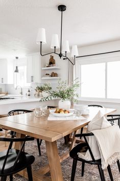 a dining room table with black chairs and white walls