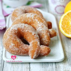 two sugared donuts on a white plate next to an orange