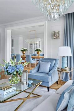 a living room filled with furniture and a chandelier above a glass coffee table