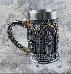 a large metal mug sitting on top of a stone counter covered in gold and black decorations