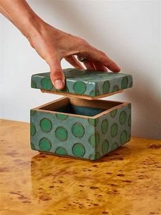 a hand reaching into a green box on top of a table