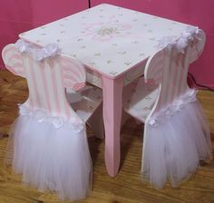 a pink and white table with tulle skirted chairs next to it on a wooden floor