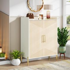 a white cabinet sitting in front of a window next to a potted green plant