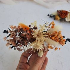 a hand holding a hair comb with dried flowers on it