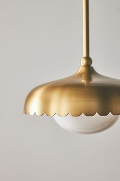 a gold colored light fixture hanging from a white ceiling with scalloped glass shades