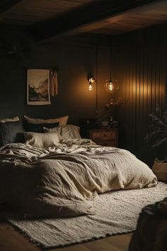 an unmade bed in a dark room with two lamps on the wall above it