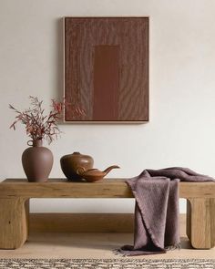 a wooden bench sitting in front of a painting and vases on top of it