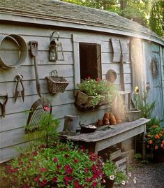 a garden shed with potted plants and gardening tools on the wall, next to a bench