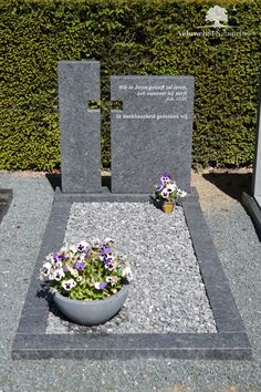 a small bowl with flowers in it sitting next to a memorial stone on the ground