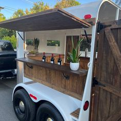 the back end of a food truck with an open door and wooden bar on it