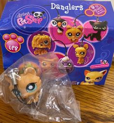 littlest pet shop keychain in plastic bag on wooden table next to packaging