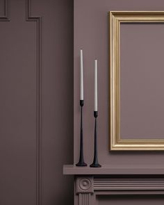 two candles are sitting next to a painting on the wall