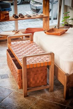 a bed sitting next to a wooden table with baskets on it