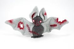 a stuffed animal bat with blood on it's body and eyes, sitting in front of a white background