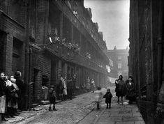 an old black and white photo of people walking down a street in the early 1900's