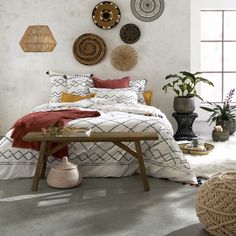 a bed room with a neatly made bed and lots of hanging decorations on the wall