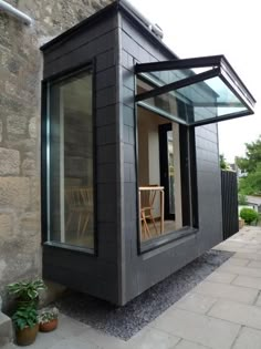 a small black building sitting on the side of a road next to a brick wall