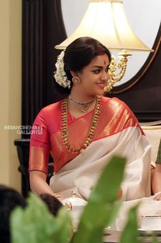 a woman in a red and white sari sitting down