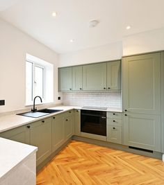 an empty kitchen with wooden floors and green cabinets