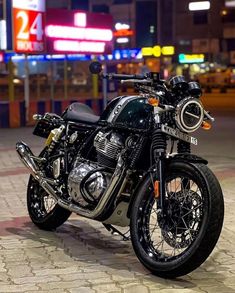 a black motorcycle parked on the street in front of some neon signs and buildings at night