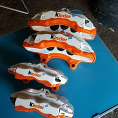 three orange and white brake pads sitting on top of a blue mat with the words kinder written on it