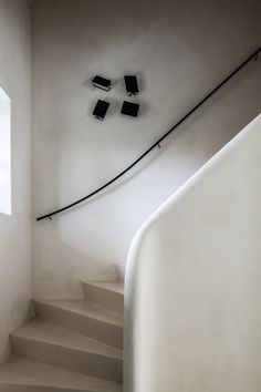 there is a white staircase with four black books on the wall and three windows above it