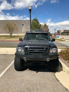 a black truck parked in a parking lot next to a street light and lamp post