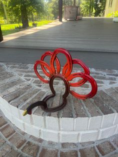 a red sculpture sitting on top of a brick walkway