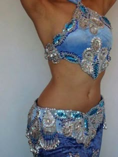 a woman wearing a blue and silver belly dance outfit with sequins on it