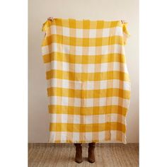 a woman is holding up a yellow and white checkered blanket with one side torn off