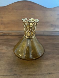 a small glass vase sitting on top of a wooden table next to a wood wall