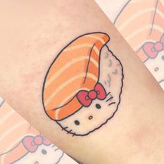 a hello kitty tattoo with sushi on it's left arm and an orange bow