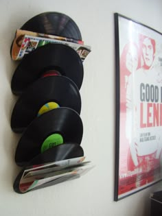 a wall mounted record player next to a magazine rack with vinyl records and magazines on it