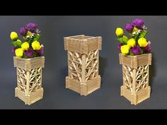 three wooden vases with flowers in them on a black surface, one is made out of bamboo