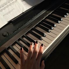 a woman's hand resting on the keys of a piano