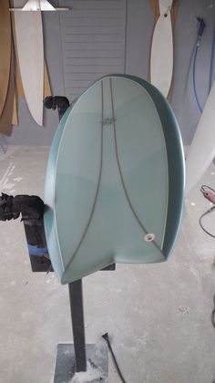 there is a surfboard on the stand in the shop and it's being worked on