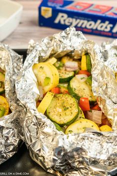 two foil wrapped food items sitting on top of a stove