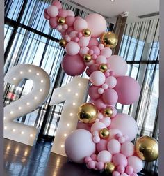 the number twenty two is made out of balloons and gold balls in front of a large window