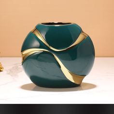 a green vase sitting on top of a white counter next to a golden object in the background