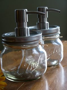 two mason jars with soap dispensers sitting on a table next to a sunflower