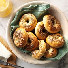 a bowl filled with bagels sitting on top of a table next to sliced lemons