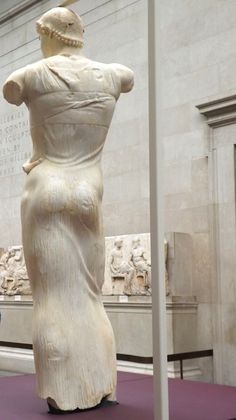 two people standing in front of a large white statue with a woman's back turned to the side