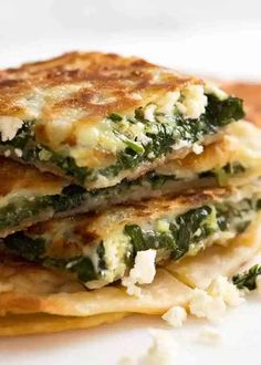 three pieces of food stacked on top of each other with cheese and spinach in the middle