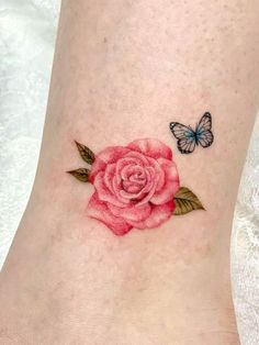 a small rose tattoo on the ankle with a butterfly flying over it and a pink flower