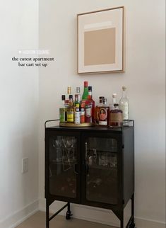 a bar cart with liquor bottles and glasses on it in the corner of a room