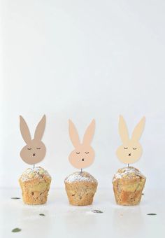 three cupcakes with bunny ears on top and one has a muffin in the middle