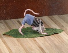 a toy rat sitting on top of a green leaf